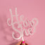 Cake topper with 'He or She?' text on a pink background