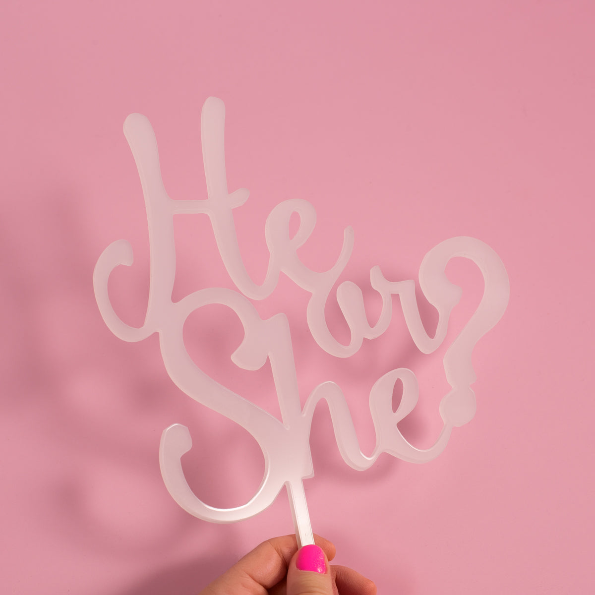 Cake topper with 'He or She?' text on a pink background