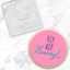 A square clear acrylic debosser with 'HIP HIP Hooray!' lettering, shown next to a round pink frosted cookie with blue and teal 'HIP HIP Hooray!' lettering on a white marble background.