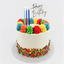A round birthday cake with white frosting, decorated with colorful piped rosettes around the top edge, multicolored sprinkles around the base, three blue candles, and a 'Happy Birthday' script topper on a white background.