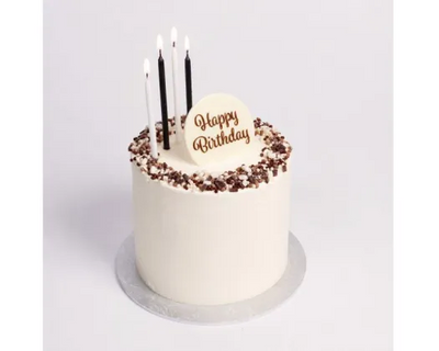 black and white candles on a cake with happy birthday plaque