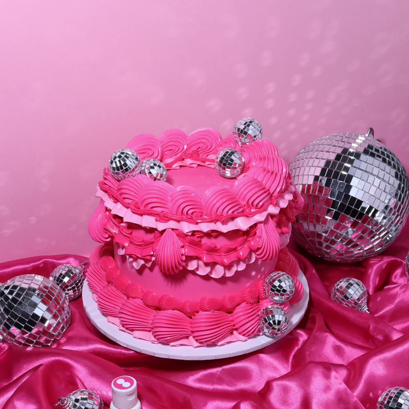 Pink cake with disco balls on a pink satin surface and pink background
