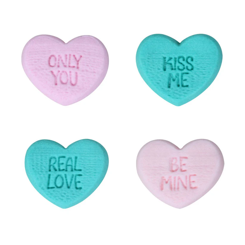 Four heart-shaped edible candy hearts with romantic messages on a white background