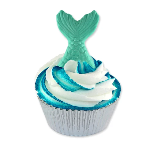 A mermaid-themed cupcake with white and blue swirled frosting, topped with a teal mermaid tail decoration, set in a silver foil liner against a plain white background.
