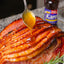 Sliced ham with a spoon drizzling glaze over it, Karo syrup bottle in the background.