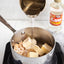 Measuring liquid being poured into a pot on a stove with Karo in the background.