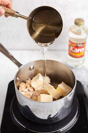 Measuring liquid being poured into a pot on a stove with Karo in the background.