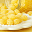 Yellow lemon flavoured hard candies on a white plate with a jar in the background
