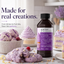 A bottle of Lorann's Better Than Exctract Cake & Cookie Emulsion stands on a marble surface next to purple berry-topped cookies, a cupcake, and ice cream scoops in a bright kitchen setting. Large text on the left reads 'Made for real creations.