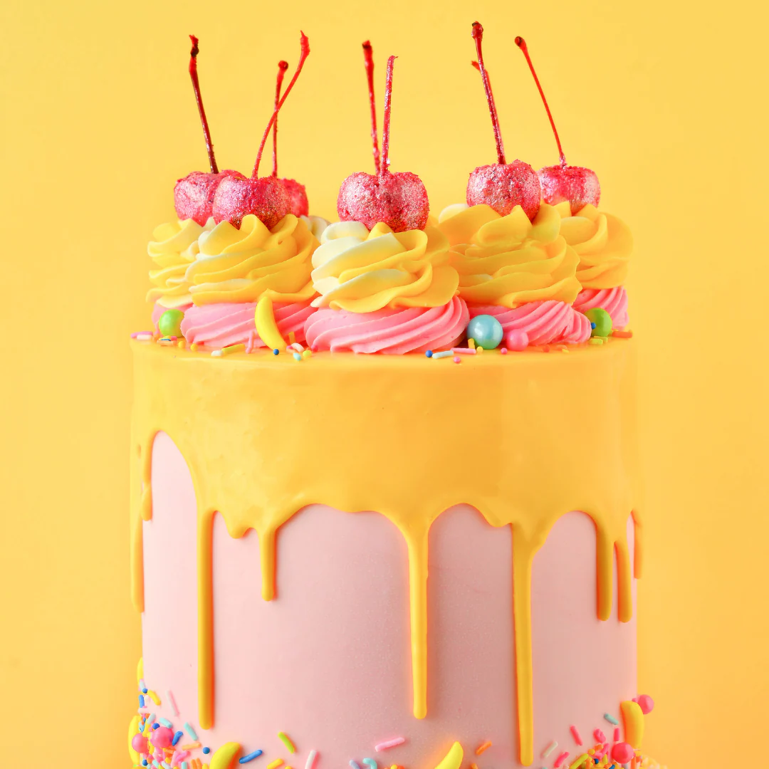 Colorful cake with yellow and pink frosting, cherries, and sprinkles on a yellow background