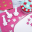 Snowflake cookie cutters pink fondant icing surface with snowflakes and a decorated cupcake.