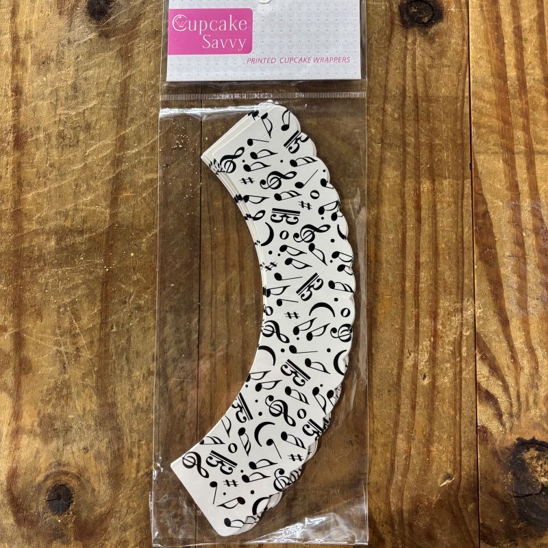Music note patterned cupcake wrapper on a wooden surface with 'Cupcake Savvy' packaging.