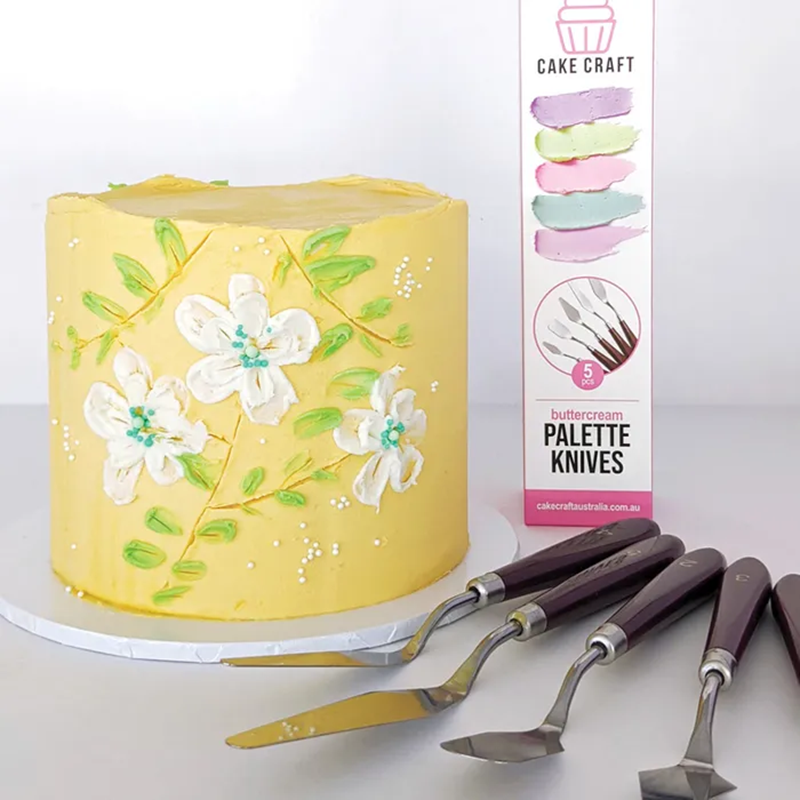 Yellow cake with floral decorations next to Cake Craft palette knives packaging