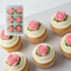 Cupcakes decorated with edible pink roses on a white buttercream swirl