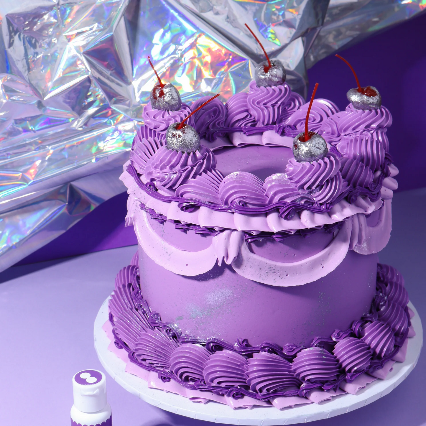 Purple cake with decorative elements on a reflective surface