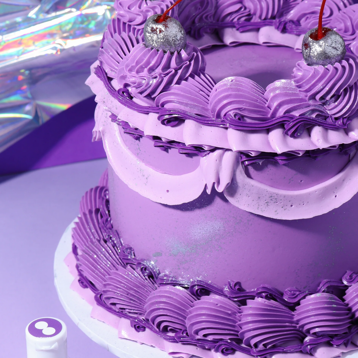 Purple cake with decorative frosting and cherries