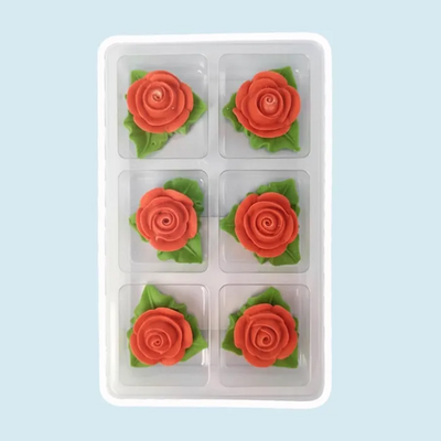 Six red rose-shaped icing decorations