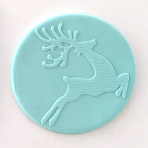 A round light blue fondant icing plaque featuring an embossed silhouette of a stag with antlers, set against a plain off-white background.