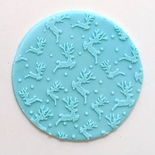 A round light blue fondant plaque with an embossed pattern of leaping deer and small dots, shown on a plain light background.