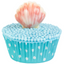 A decorative cupcake with a turquoise blue polka-dot wrapper, light blue pearl-like frosting, and a pink-and-white seashell topper on a plain white background.