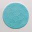 A round turquoise blue fondant plaque featuring a repeating scallop or wave pattern, shown on a plain off-white background.