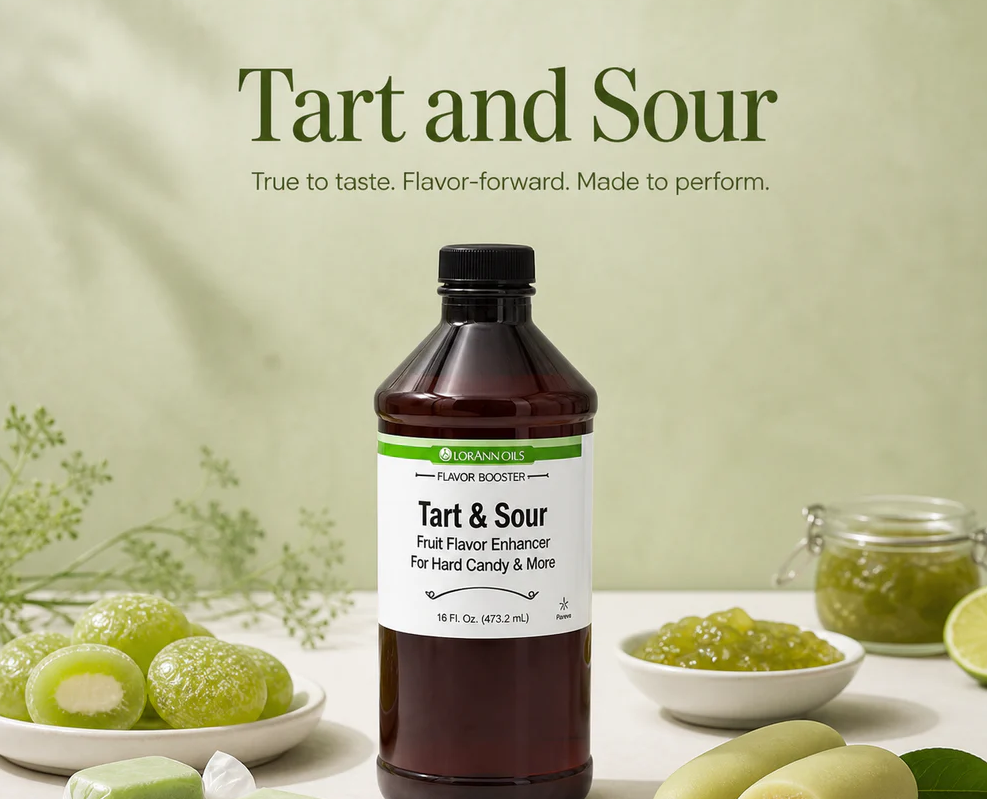 A bottle of Lorann Tart and Sour fruit flavor enhancer centered on a light green background, surrounded by green fruit, lime slices, and small bowls of the green flavoring paste. Large text at the top reads 'Tart and Sour' with the tagline 'True to taste.