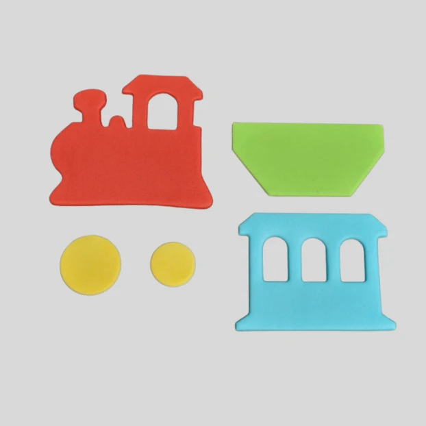 Three colorful fondat pieces shaped like parts of a train, including a red locomotive, a light blue passenger car, and a green cargo container, with two yellow circular wheels shown separately, arranged on a light gray background.