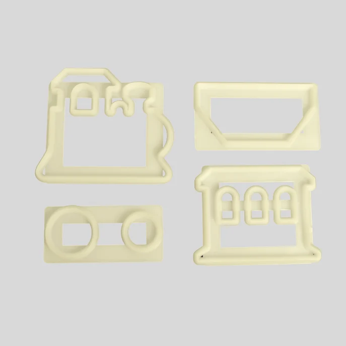 Four pale cream-colored plastic fondant cutter components or molds arranged on a light gray background.