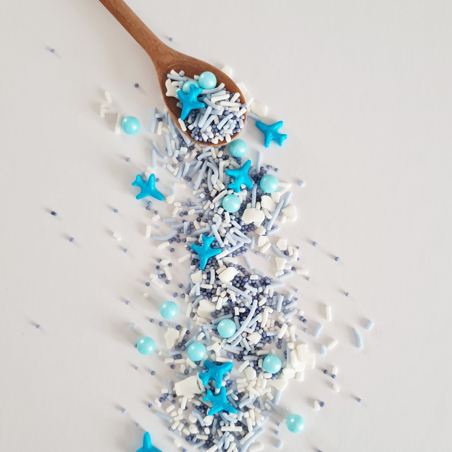 Wooden spoon with blue star-shaped sprinkles on a light gray background