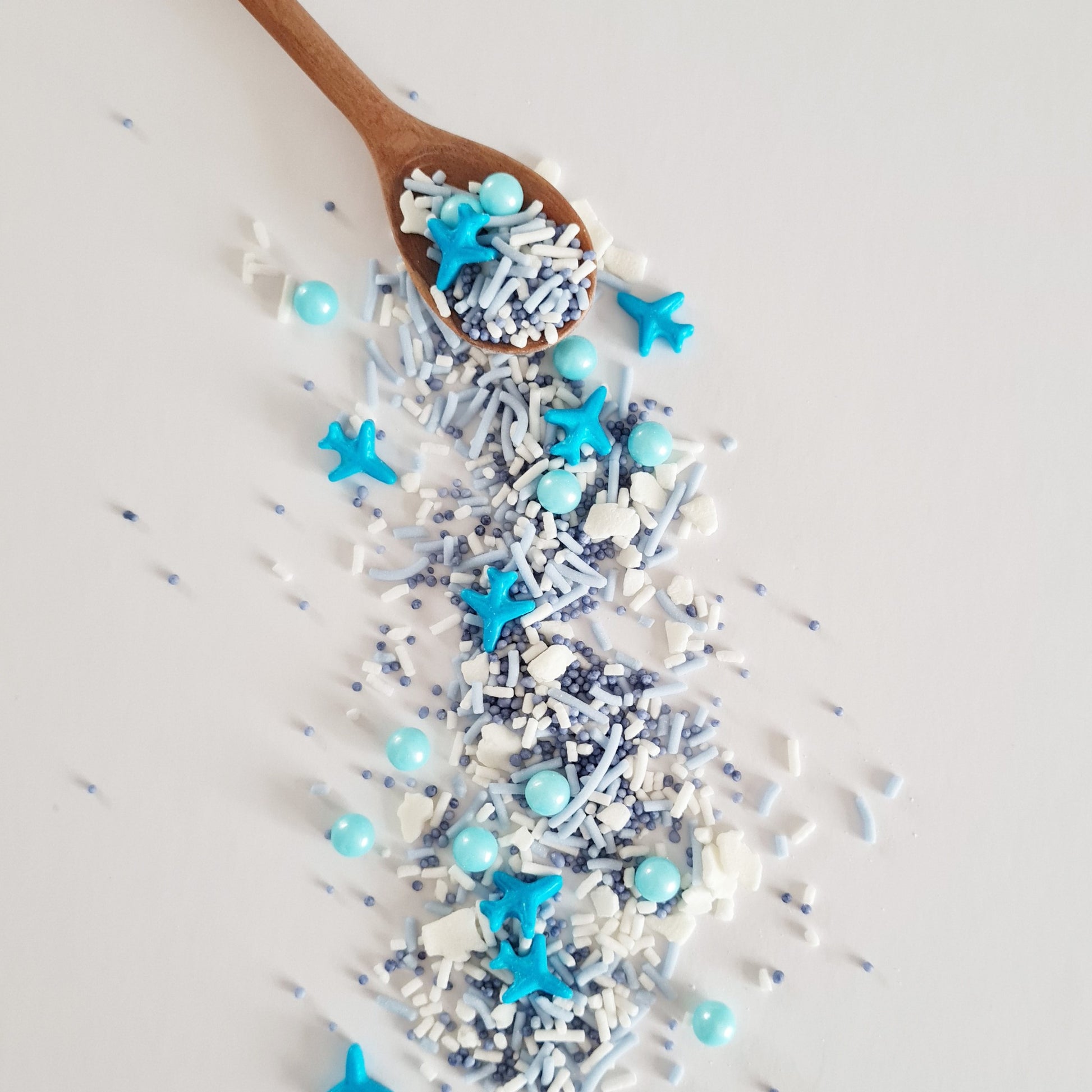 Wooden spoon with blue star-shaped sprinkles on a light gray background
