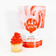 Bag of Cake Cream Vivid Red frosting next to a cupcake with red frosting on a white background