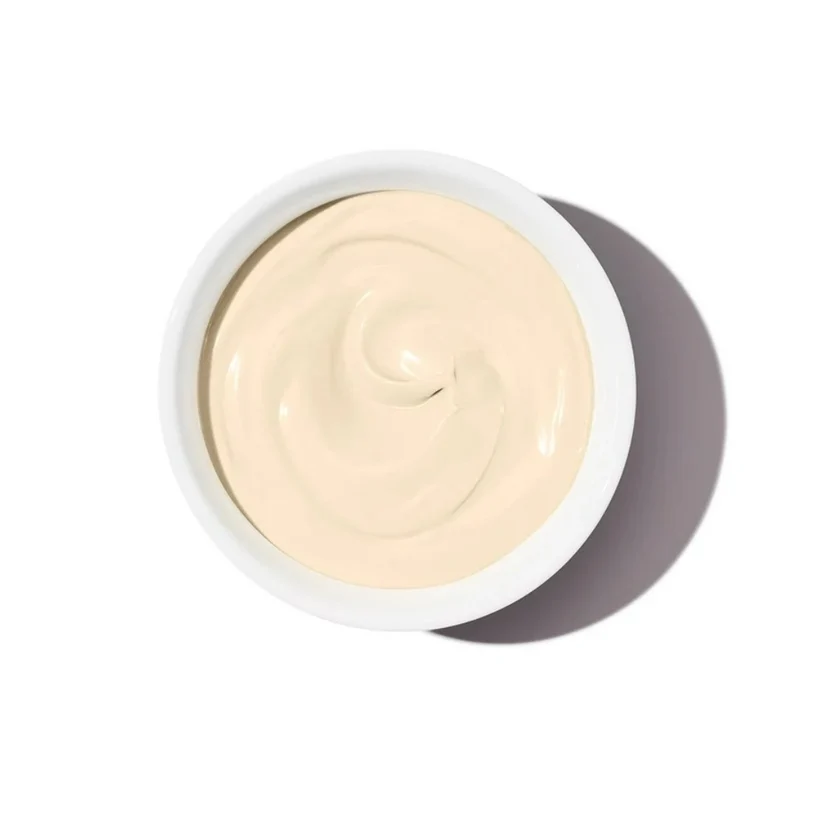 A top-down view of melted white chocolate swirled inside a white round jar, casting a soft shadow on a clean white background.