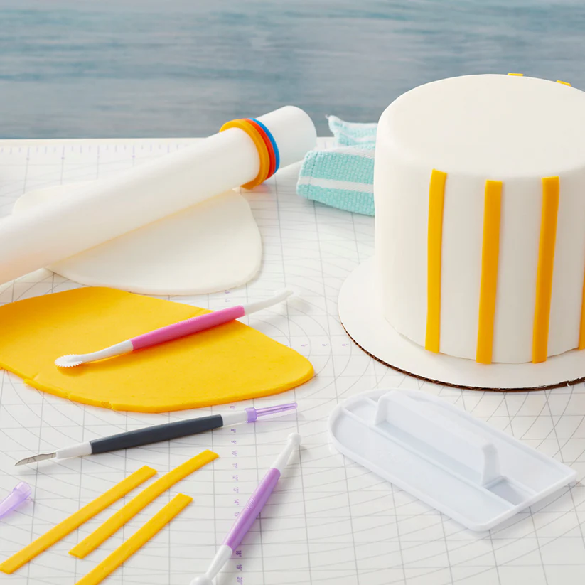 Wilton wide rolling pin along side a fondant cake in progress with modelling tools