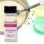 A small bottle labeled Lorann Oils Cake Batter Flavor, with a measure of 1 dram indicated, placed on a white bench next to a mixing bowl and baking molds.