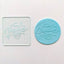 A clear acrylic debosser tool that reads, Happy Valentine's day. Alongside a teal fondant plaque showcasing the design