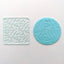 Clear acrylic debosser with a pattern of hearts all over it. Alongside a fondant plaque in blue showcasing the design