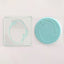 A clear acrylic embossing tool in the shape of an oval frame, alongside a teal fondant plaque embossed with an oval frame design
