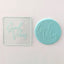 A clear debosser with 'Good Vibes' text imprinted on it, placed on a light blue background.