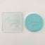 A clear debosser with a blue fondant example plaque, and a design that reads 'MISSING YOU' with heart shapes on each side of the text.