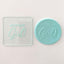 Clear debosser tool with "birthday girl" along with an example of teal fondant  used to make it