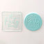 Clear acrylic debosser tool alongside a fondant plaque made using it. It reads It's Party time