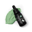 A 15ml dropper bottle of Sprinks Sage Gel Colour, with a bit of green food coloring visible in the background.