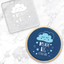 Clear debosser with blue and white design imprinting on a marble background, reading 'Dream Big Little One' with a cloud illustration above the text.